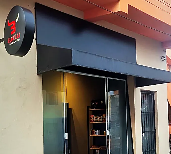 Fachada da El Bulli: placa redonda com o logo, toldo escuro e a vitrine de vidro